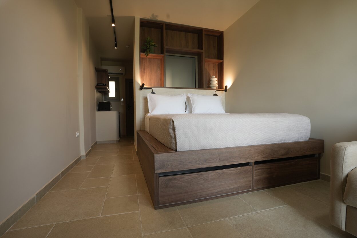The bed — olive linen against a woven headboard