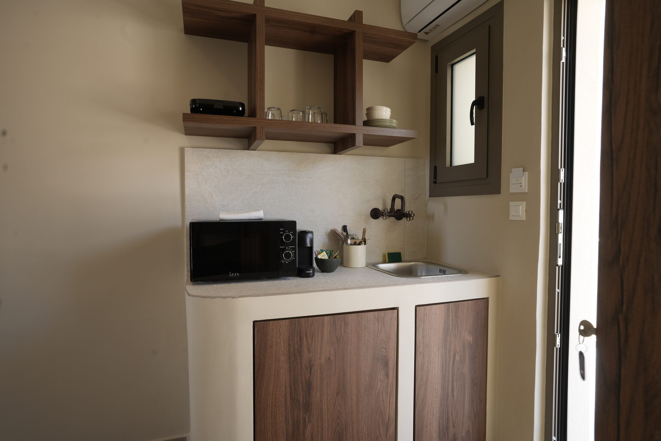 The kitchenette — induction, sink, a shelf of cups